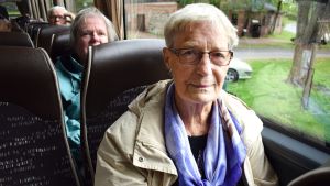 Lisbeth Nyberg tycker det bästa är att få träffa människor. Lisbeth Nyberg, som har på sig en beige jacka och lila scarf sitter i en buss.