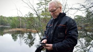 Jägarna på ön försöker hjälpa varandra med att ha koll på var vargarna finns, speciellt under jakttider. Bo vilander framför en sjö, tittar ner i sin mobiltelefon.