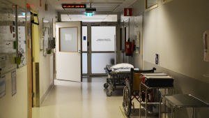 Operationsverksamheten är kostnadseffektiv och av hög kvalitet, säger överläkare Henna Turunen. En korridor på Borgå sjukhus. Invid den högra väggen står en sjukhussäng och en rullstol. Till vänster är en öppen dörr.
