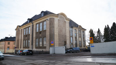 Ett stenhus i flera våningar invid en solbelyst gata.