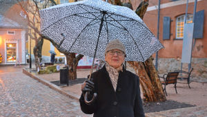 Vem sprider mer julstämning? Juldekorationer eller Marianne Reijonen? En dam med leopard-mönstrat paraply står i Gamla stan i Borgå.