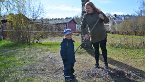 Isabella Törnblom och sonen Vidar. En kvinna krattar. Framför henne står en liten pojke och tittar in i kameran.