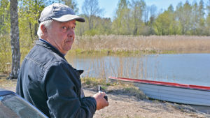 Peter Wallén. En äldre man står på en strand och håller i en pipa. Han ser sig över axeln och in i kameran.