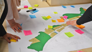 Företagarna fick bekanta sig med utkasten till detaljplan och skriva in kommentarer och åsikter på lapparna. På bilden syns en ritning av bostadsområdet. Utanpå det har någon fäst post-it lappar med kommentarer. Flera personer har sina händer på pappret.