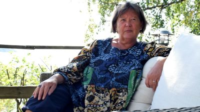Ghita Edmark i ett somrigt landskap med gröna björkar i bakgrunden.