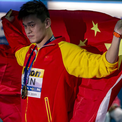 Sun Yang håller upp den kinesiska flaggan bakom sig.