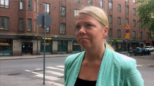 Reetta Putkonen, chef för trafik-och gatuplanering i Helsingfors. En kvinna med blont hår och turkos rock står vid en gatukorsning.