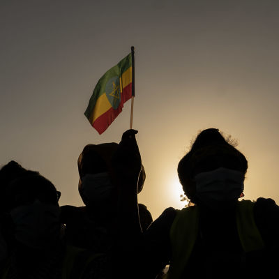 Etiopiens flagga vajar och i förgrunden svarta siluetter av människor i militär klädsel