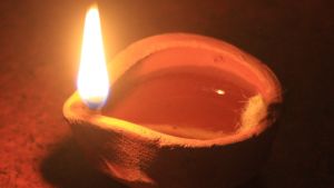 Indisk oljelampa av lera lyser vackert under hinduernas ljusfest Diwali. Närbild av en indisk oljelampa gjord av lera. Varmt, orange-färgat sken på bilden.