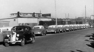 Amerikkalaisia autoja tienlaidassa mustavalkoisessa kuvassa.