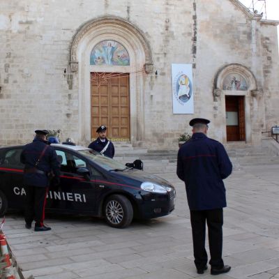 Poliser vid en polisbil utanför en kyrka i Grumo Appula. 