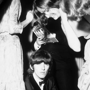 1965 kunde man inte ännu betala för att få The Beatles hem till sig för en privat spelning utan man måste köa och trängas för en autograf. På bilden George Harrison som skriver autografer på premiären av filmen Help! den 29.7. 1965 i London. Gerorge Harrison i The Beatles skriver autografer i London 29.7.1965 på premiären av filmen Help!