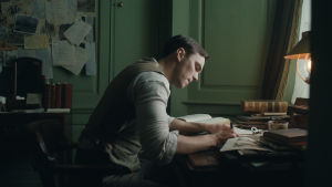 En bild säger lika mycket som ett ord. Tolkien (Nichols Hoult) sitter och skissar vid sitt skrivbord.