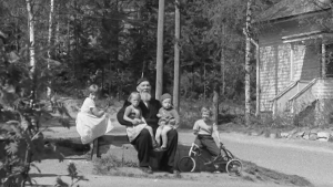 Taata istuu kivellä lasten ympäröimänä.