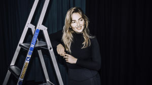 Erika Sirola vietti yläkoulun taksvärkkipäivän Kaiku-studiolla, ja siitä tuli hänen ensisysäyksensä musiikkialalle. Erika Sirola nojaa kädellään tikkaisiin.