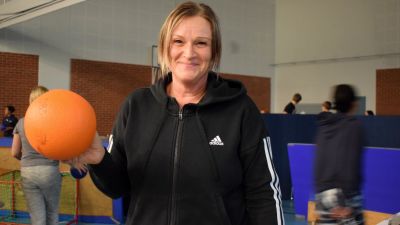 Jaana Eriksson med en boll i handen i en gympasal full med ungdomar.