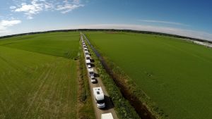 Asuntoautoja jonossa Suviseuroihin pienellä peltotiellä.