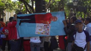 Ihmiset kannattelevat vaakatasoon käännettyä Hugo Chavezin kuvaa
