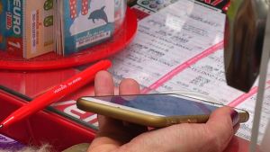 Kommunbiljetten laddas via en app ner i telefonen. En hand håller i en guldfärgad telefon.