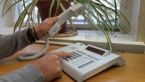 I fjol räknade man med att en person satt i samjourens telefonkö 90 minuter i snitt. En hand lyfter telefonluren och ett nummer trycks.