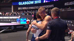 Träningskompisarna Heikki Niva och Oskar Kirmes och deras tränare Mati Kirmes efter avslutad tävling i VM i artistisk gymnastik i Glasgow 2015. Gymnasterna Oskar Kirmes och Heikki Niva kramar varandra efter avslutad tävling.