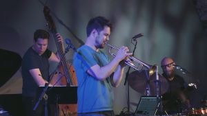 Verneri Pohjola på trumpet, tillsammans med Antti Lötjönen, bas och Mika Kallio, trummor Trumpetisti Verneri Pohjola ja bändi lavalla Viapori Jazzissa 2016. Kuva ohjelmasta Yle Live: Verneri Pohjola.