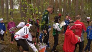 Kontrollen är vid en sten. Sprintträning i Kuortane under Leimaus-lägret. Flera barn i närheten av en orienteringskontroll i skogen.