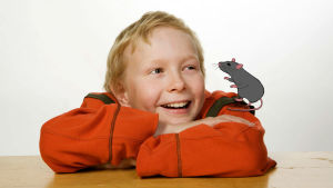 Poika istuu kädet ristissä. Piirretty rotta olkapäällä.