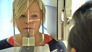De ny apparaterna har mindre stråldoser än de gamla. Men undersökningarna kostar pengar ändå.. En kvinnlig patient är med om en ortopantomografi eller en så kallad panoramaröntgen.