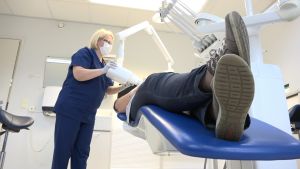 Bitewing-fotografiet tas i tandläkarstolen. En tandsköterska tar en bitewingröntgen på en patient.