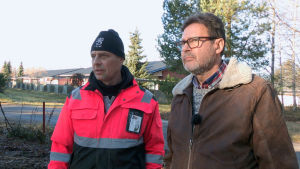 Juha-Pekka ja maanrakentaja Kari Vaajakivi silmäilevät Juha-Pekan vanhempien talon tyhjää tonttia. Kaksi miestä katsovat rakennuksen tonttia