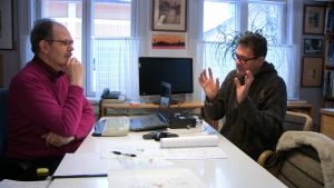Juha-Pekka esittelee arkkitehti Jukka Koivulalle unelmiaan talohankkeesta. Miehet neuvottelevat talon piirrustuksista