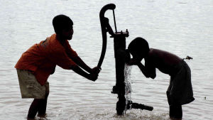 Intialaiset lapset juovat vettä pumppukaivosta.
