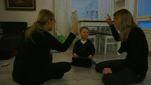 Sandra, Kevin och Janina sjunger helikopter sången. Sandra, Kevin och Kevins mamma sitter på golvet och sjunger och tecknar.