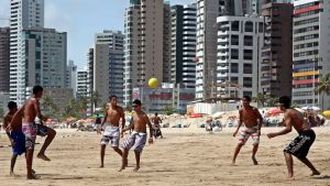 Brasialaiset pojat pelaavat jalkapalloa rannalla