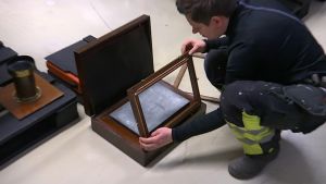 Museimästaren Tina Blomqvist inspekterar en kopieringsmaskin. kvinna med museiföremål