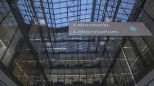 Den innersta delen av byggnaden nås endast av mycket lite dagsljus. En skylt där det står "laboratorie". I bakgrunden ser man en byggnad med stora fönster.