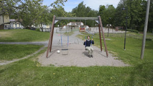 Henrik på sin gamla skolgård. En man sitter i en gunga på en skolgård. I bakgrunden syns en lekplats.