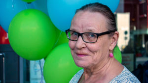 Keski-ikäinen nainen ilmapallojen edessä, kasvokuva.