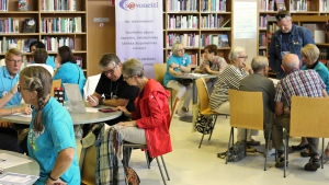 Vertaisopastajat auttavat senioreja tietotekniikassa Kuopion kirjastolla Nettiä ikä kaikki -tapahtumassa. Mukana myös Ylen tekniikkavastaava.