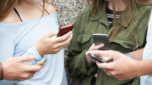 Majoriteten av de unga har lite dåligt samvete på grund av skärmtid. Ungdomar står och tittar på sina mobiltelefoner.