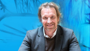 Kuvassa on Marco Mäkinen sinisävyiden taustan edessä