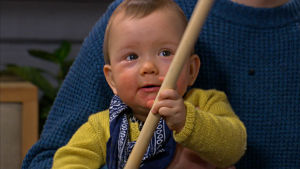 Tio månader gamla Signe försöker lära sig att hänga i en käpp. En baby leker med en käpp.