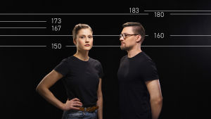 Nainen ja mies seisovat selät vastakkain, taustalla mitta-asteikkoa symboloivaa grafiikkaa.
