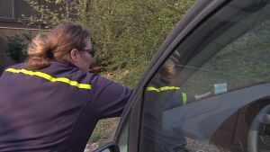 En parkeringskontrollant placerar en kontrollavgiftslapp på en felparkerad bil.