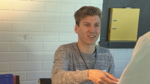 Valförrättare Axel Harju ger tillbaka identitetsbeviset till en kvinna som nyss har röstat. En man i grå tröja hjälper en person som ska rösta.