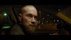 Lyhytelokuvan päähenkilö (Jukka Kärkkäinen) autossa illalla 