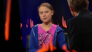 Thunberg sitter som gäst hos Skavlan. Greta Thunberg intervjuas av Fredrik Skavlan. I mitten av bilden syns Thunberg och i högermiljö Skavlan.