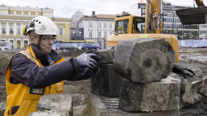 Arkeolog Kari Uotila tar provbitar från stock, de doftar trä. arkeologiska utgrävningar i Åbo, torget, Kari Uotila ansvarar för utgrävningarna
