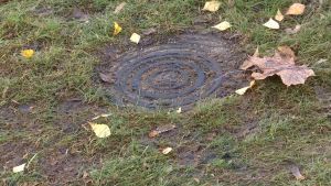Här under väntar rören som ska hämta elkablar till en laddningsstation i Tallmoparken i Karis. Ett lock i en gräsmatta där det ska kunna byggas laddningsstation för elbil.